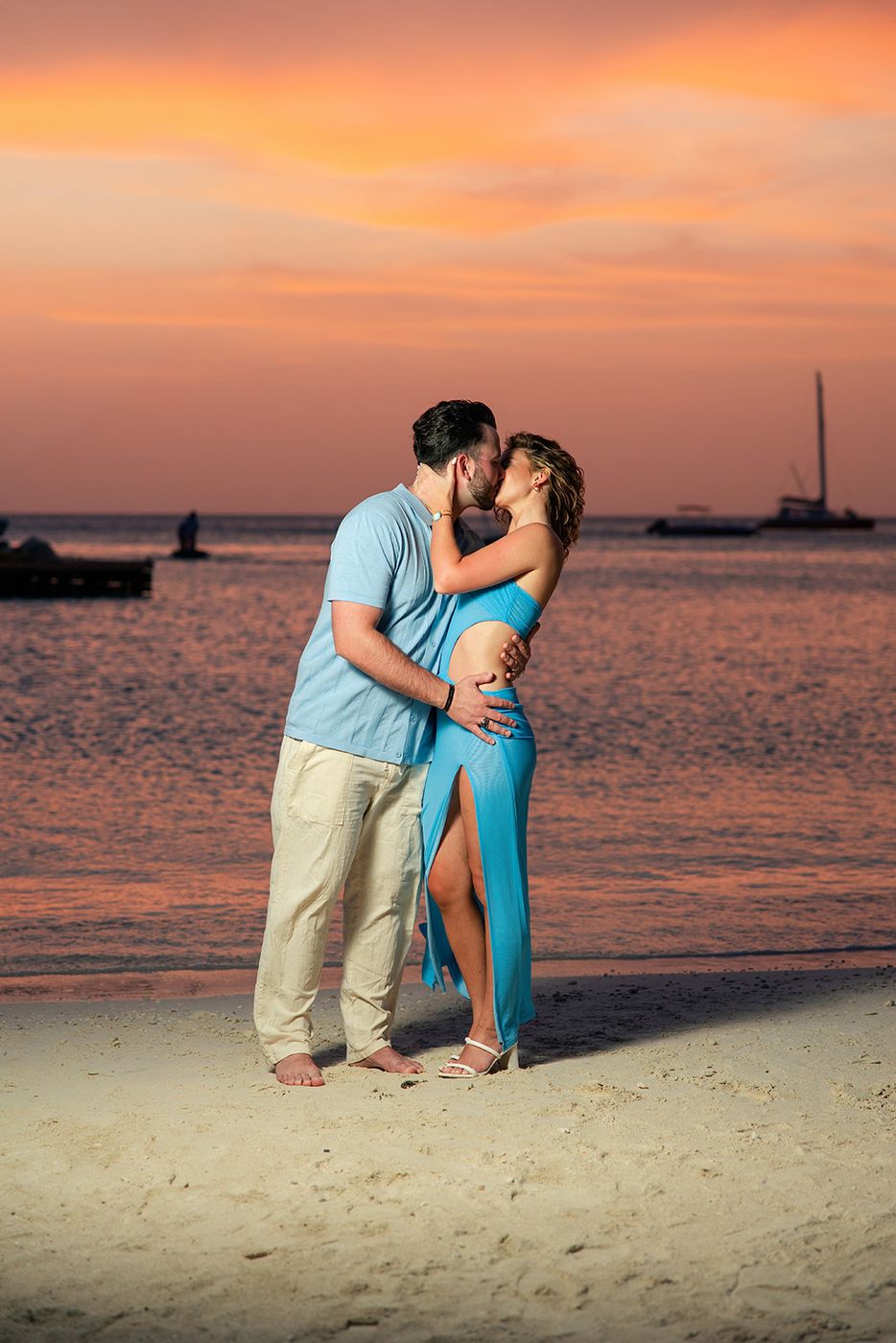 Couple kissing on the beach under an orange sunset sky
